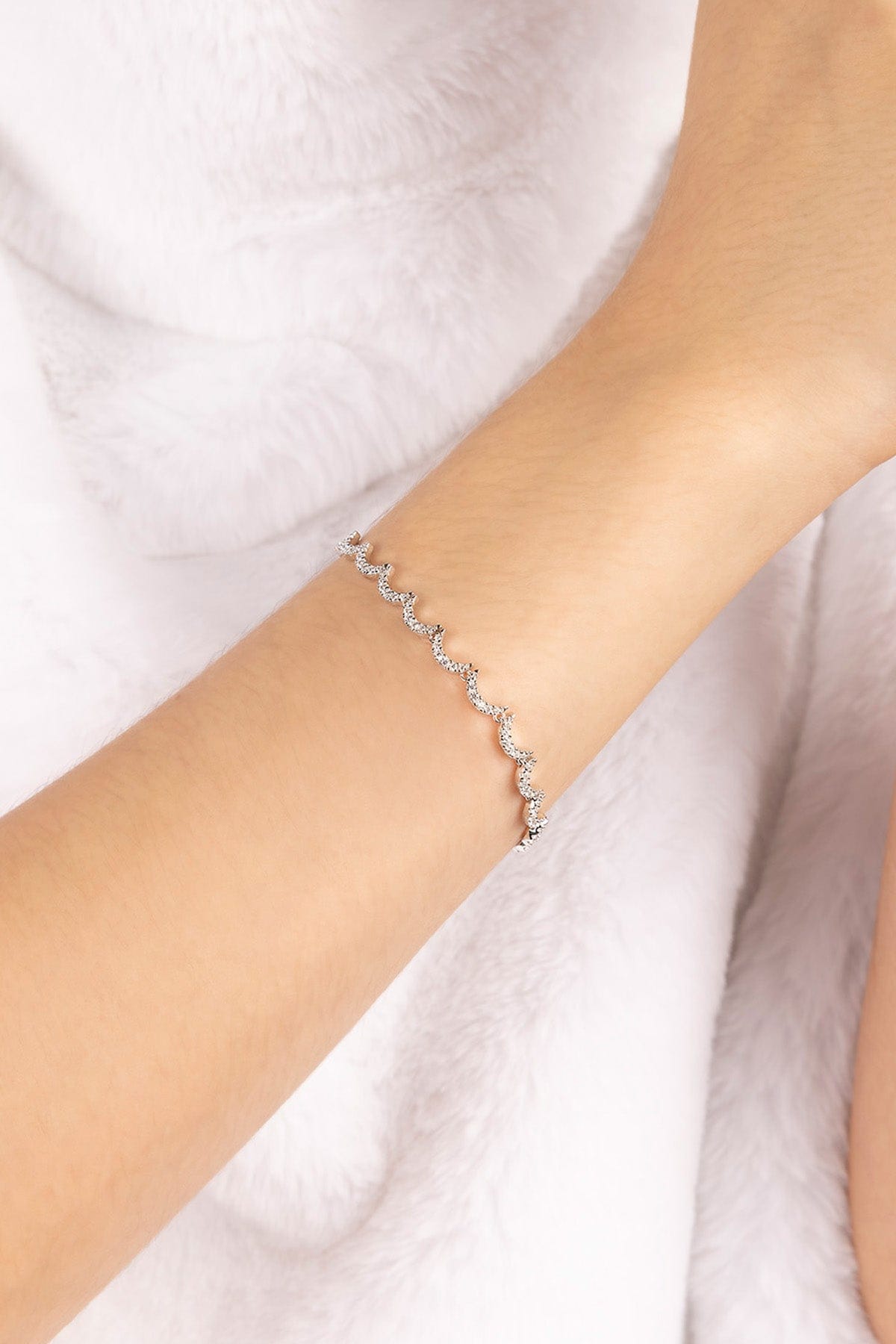 Silver bracelet on a person's wrist against a white background