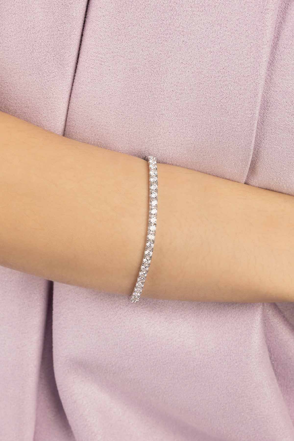Silver bracelet on a wrist against a light pink background