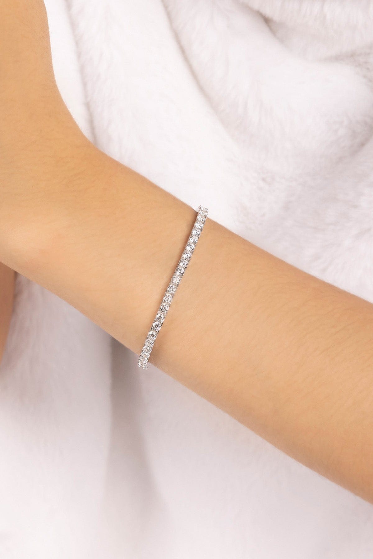 APM MONACO silver tennis bracelet on a person's wrist with a white background