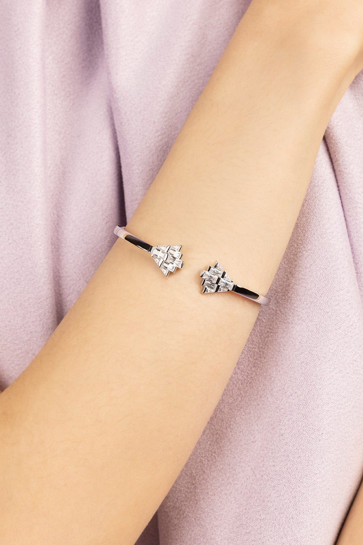 APM MONACO silver bracelet with art deco design on a person's wrist against a soft pink background