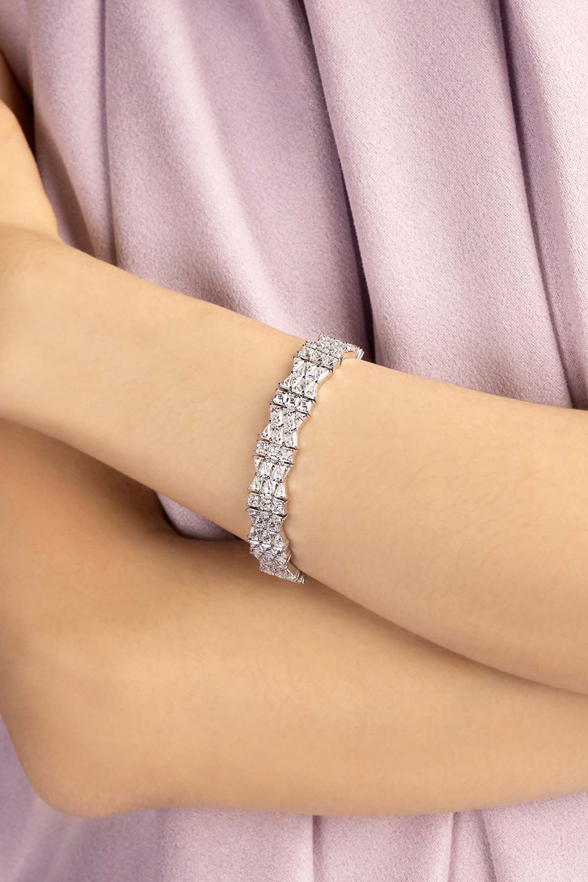 Silver bracelet on a person's wrist with a soft pink fabric background