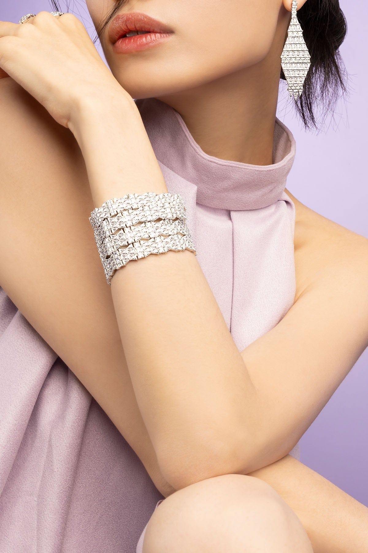 Silver bracelet on a person's wrist with a soft pink fabric background
