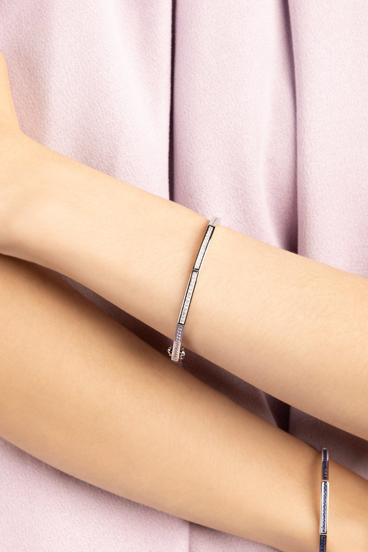 Silver bangle paved with white zirconia stones worn by model wearing purple shirt