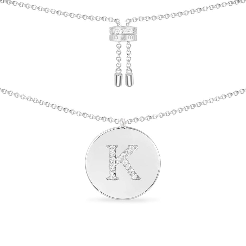 Necklaces APM Monaco, white-tone chain necklace with a round pendant featuring a pavé-studded letter K and sparkling stones.