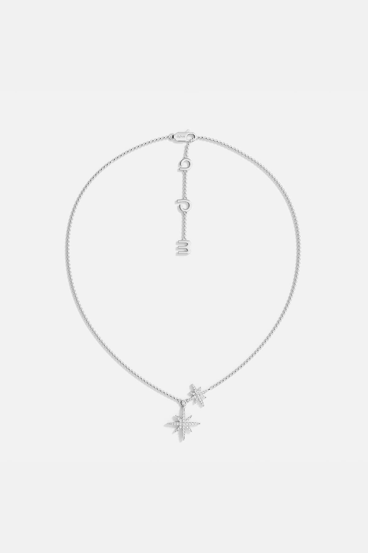 Silver necklace with star-shaped pendants on a light gray background