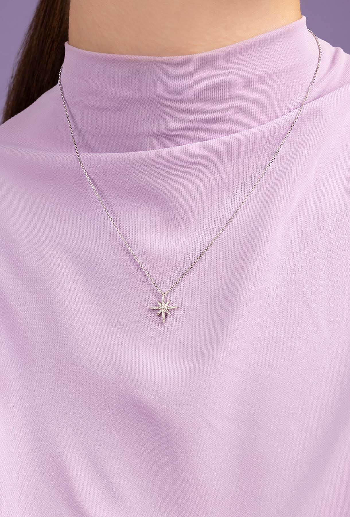 Star-shaped necklace on a person wearing a light purple top