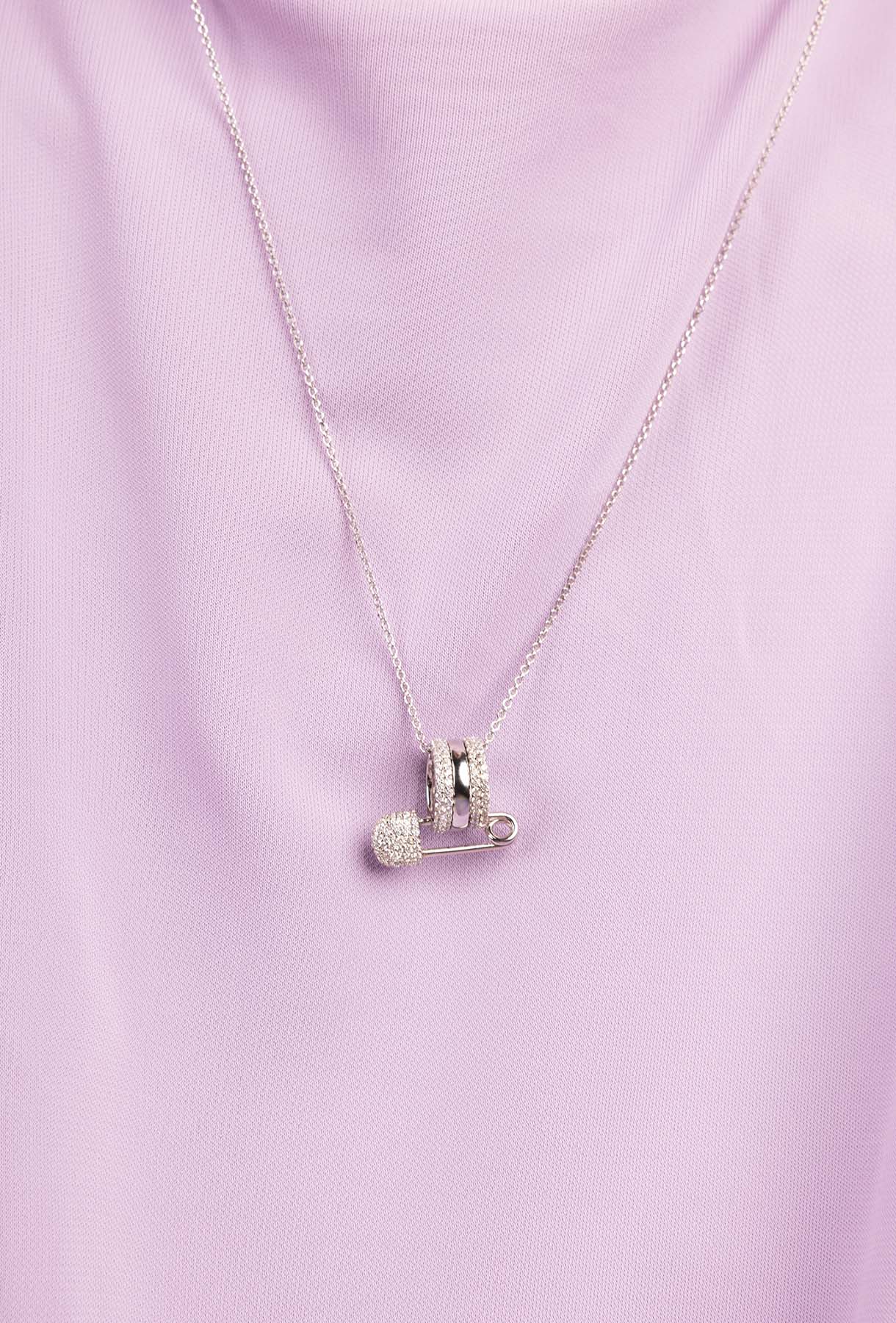 Silver necklace with a pendant on a light purple fabric background