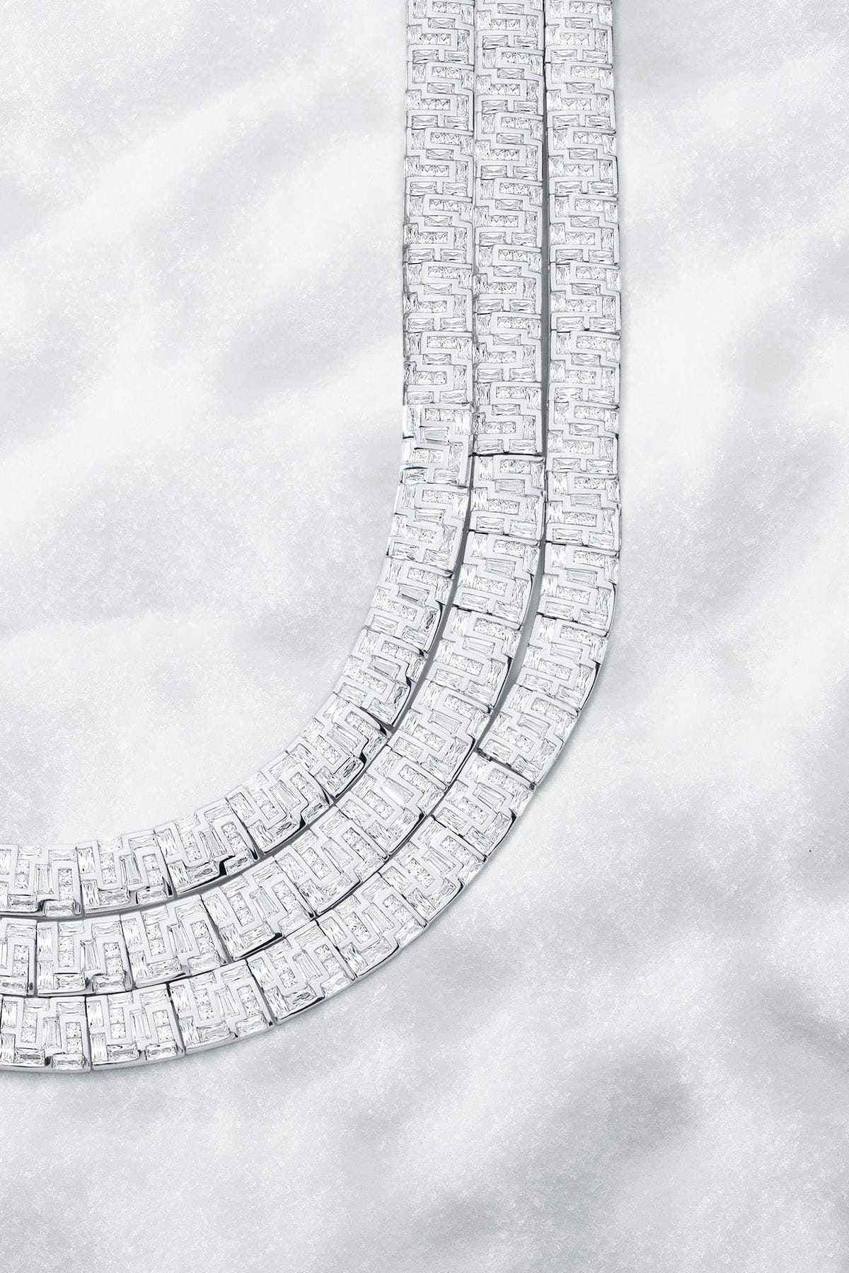 APM MONACO labyrinth necklace in silver on a light gray snowy background