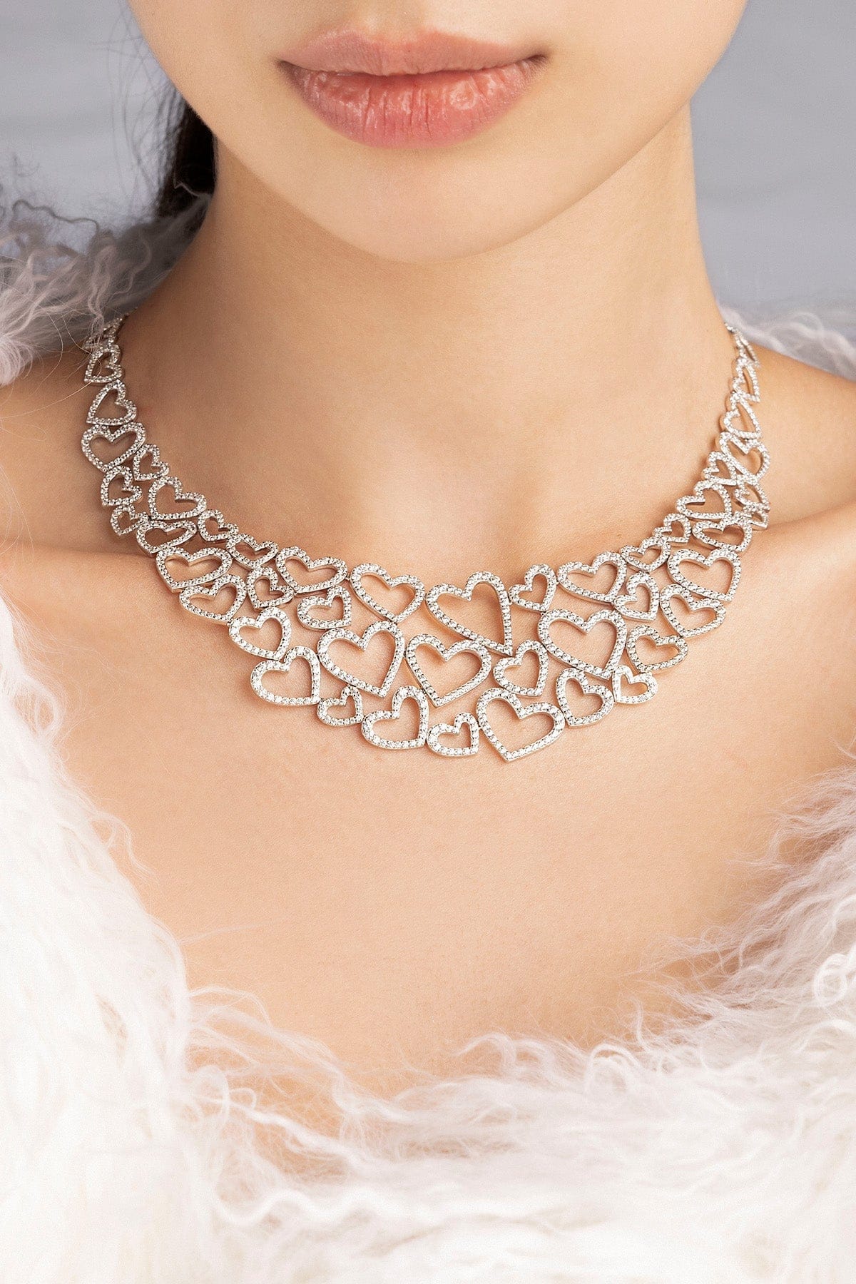 Silver heart-shaped necklace from APM MONACO worn by a model with a soft focus background