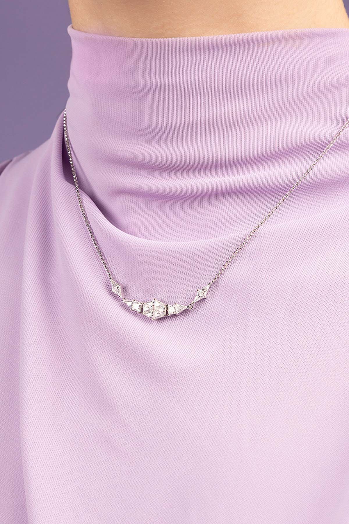 Necklace with a zirconia pendant on a person wearing a light purple top against a matching background
