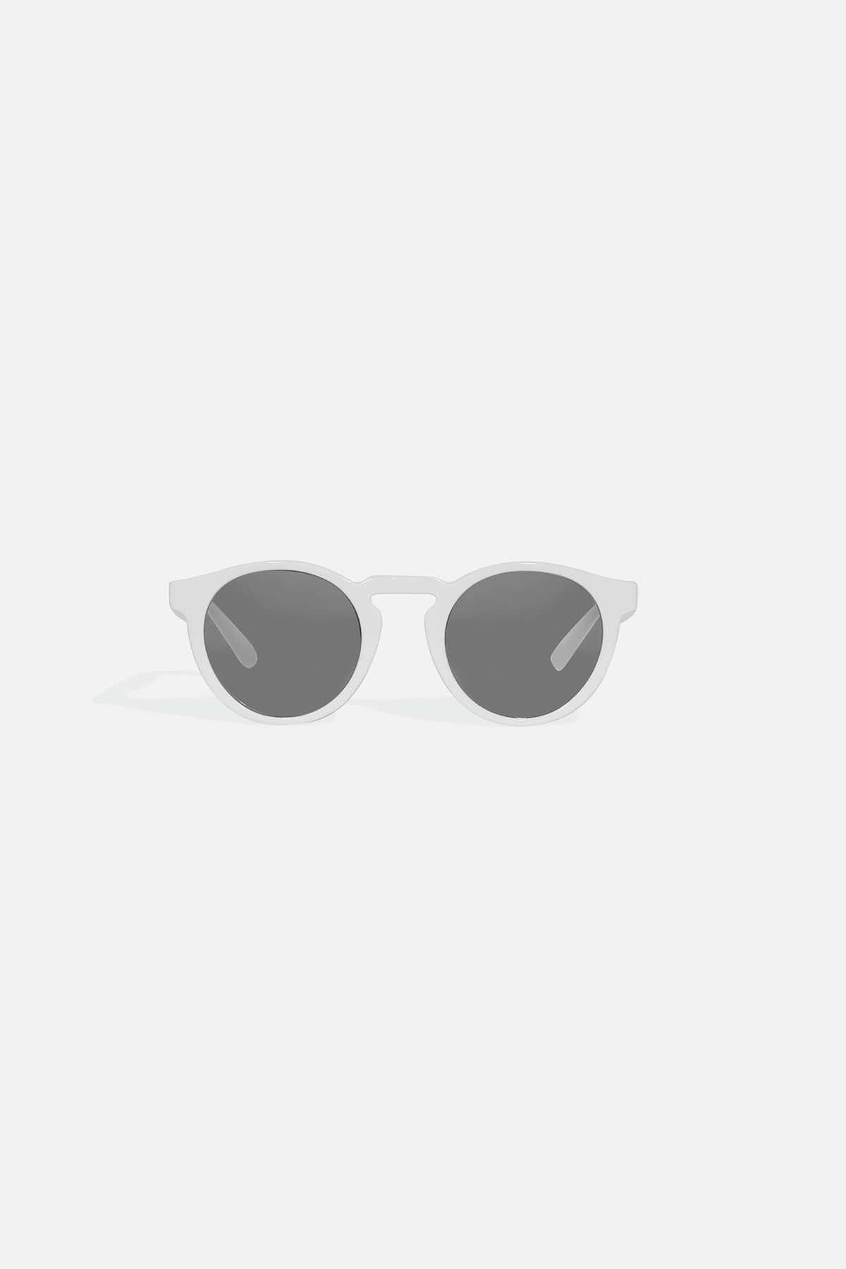 APM MONACO sunglasses with white frame and dark lenses on a light gray background