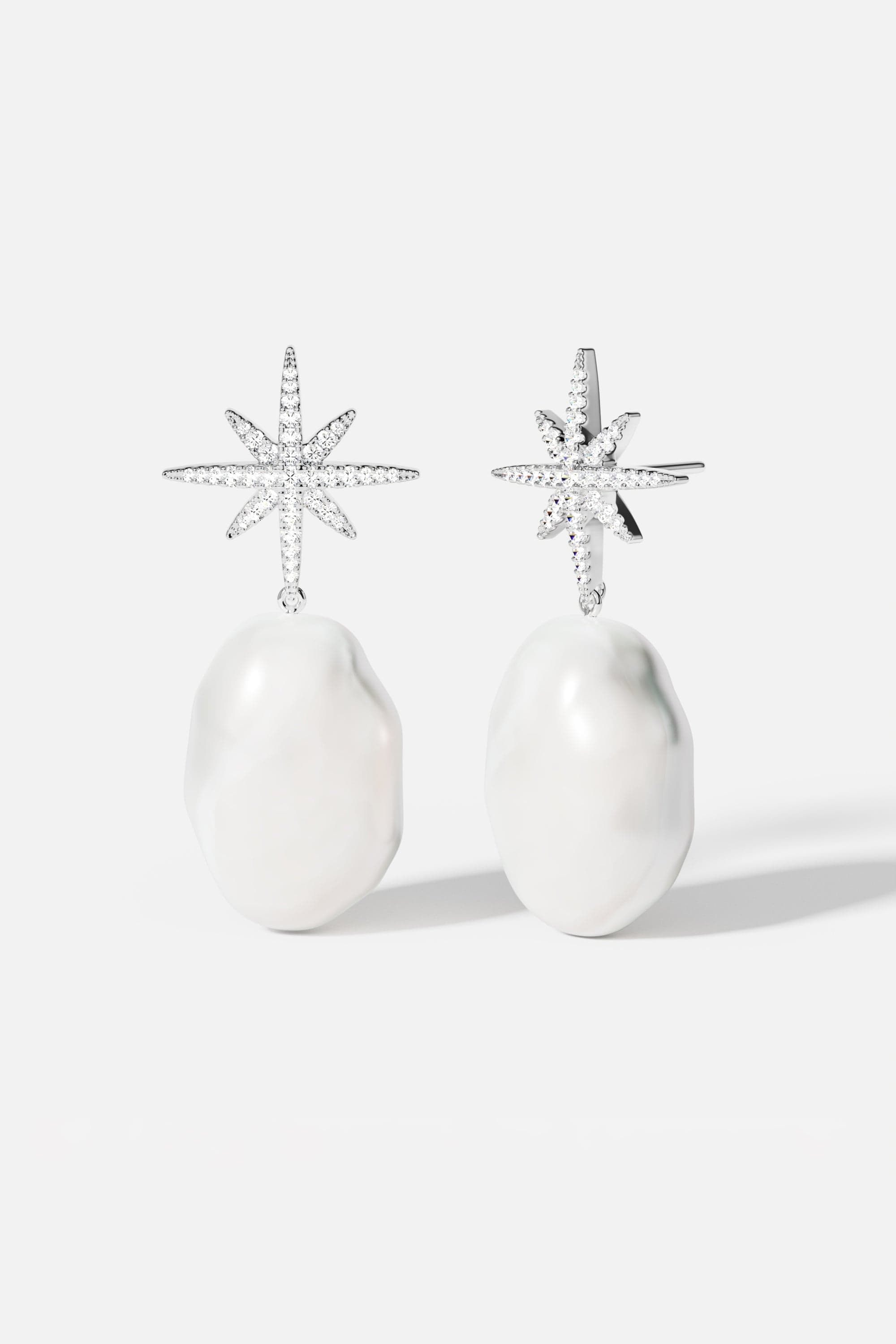 Earrings APM Monaco: pavé star earrings with white baroque pearl drops on silver-tone metal.