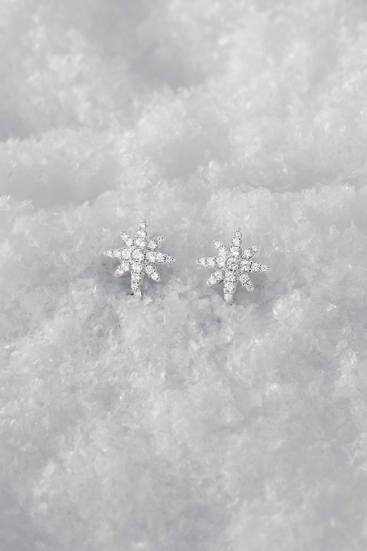 Silver snowflake earrings on a textured gray surface