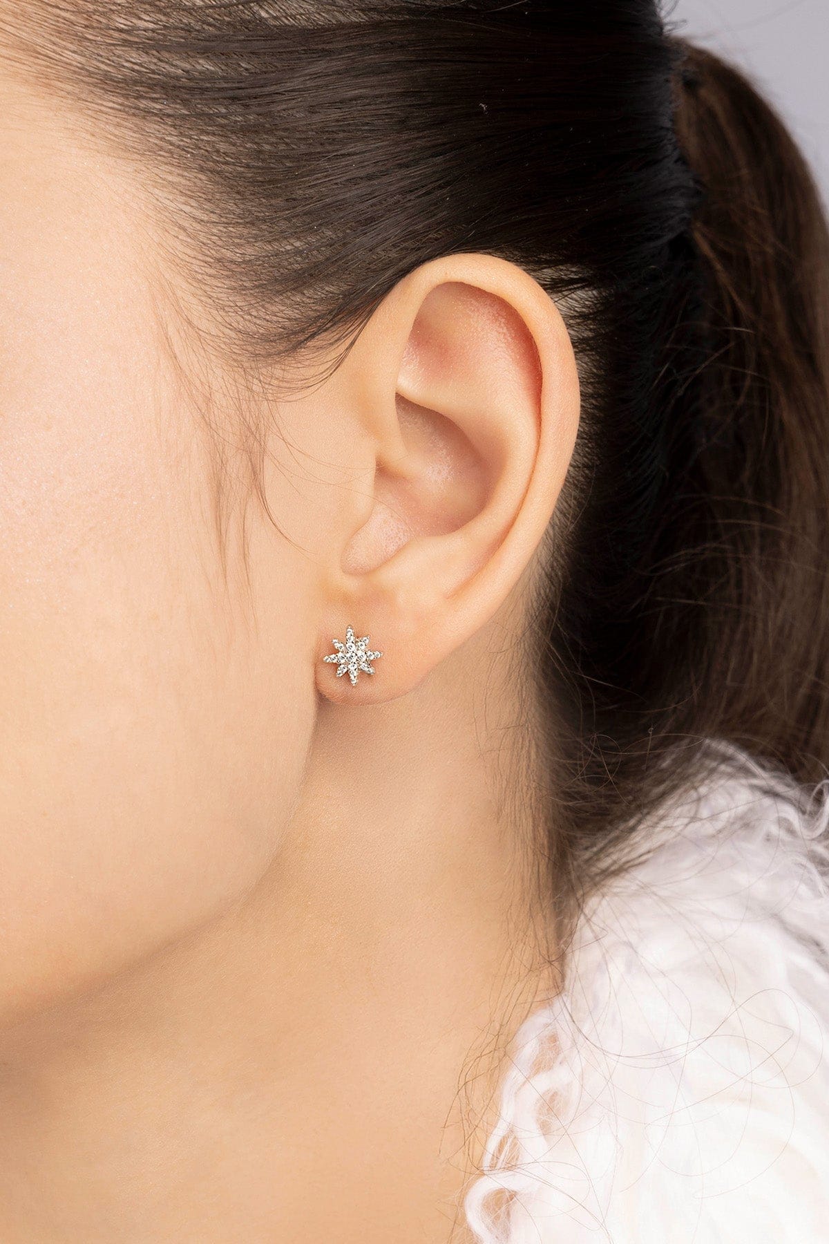 Close-up of an ear wearing a stud earring with a blurred background