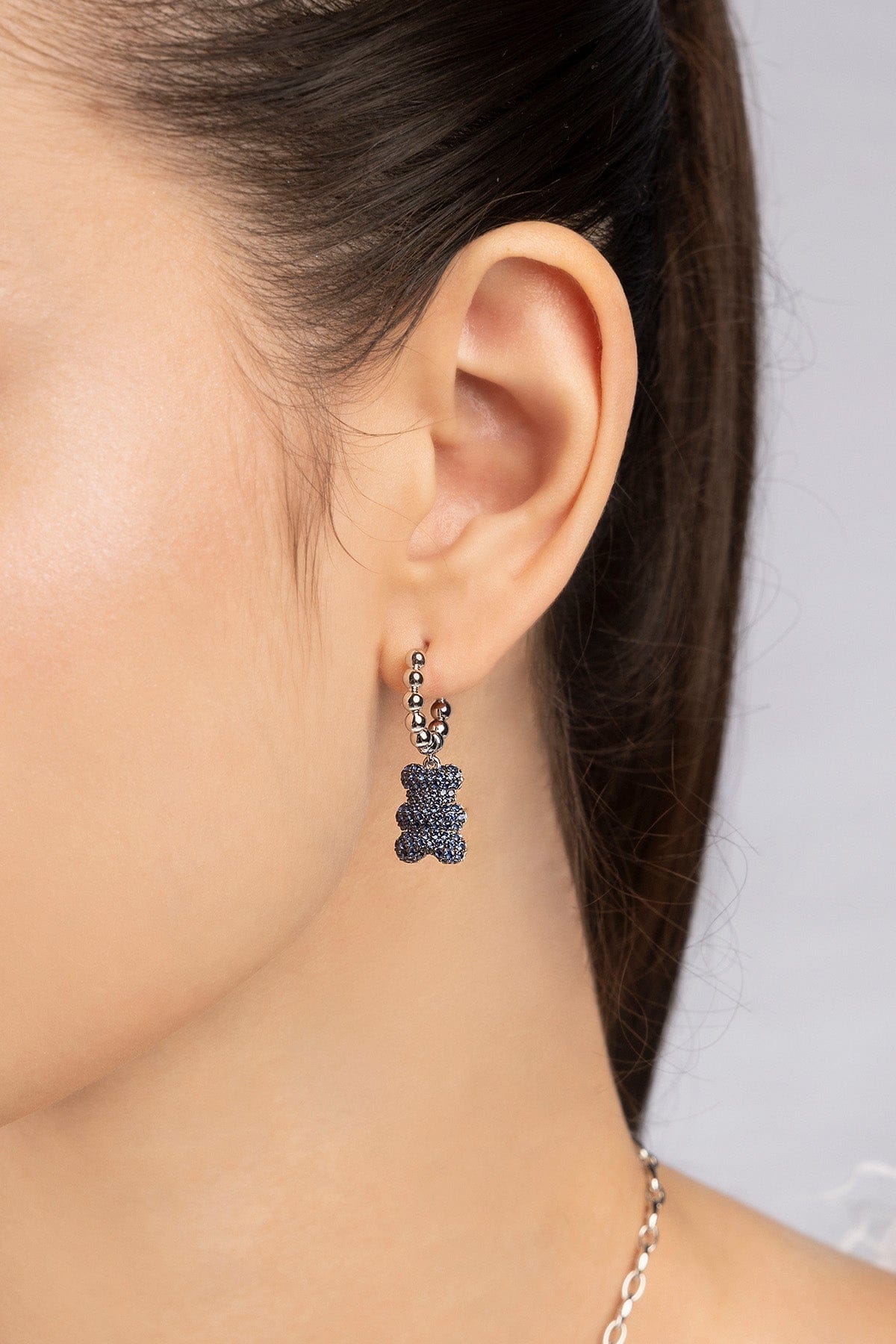 Close-up of an ear wearing a silver earring with baby yummy bear hoop design worn on model