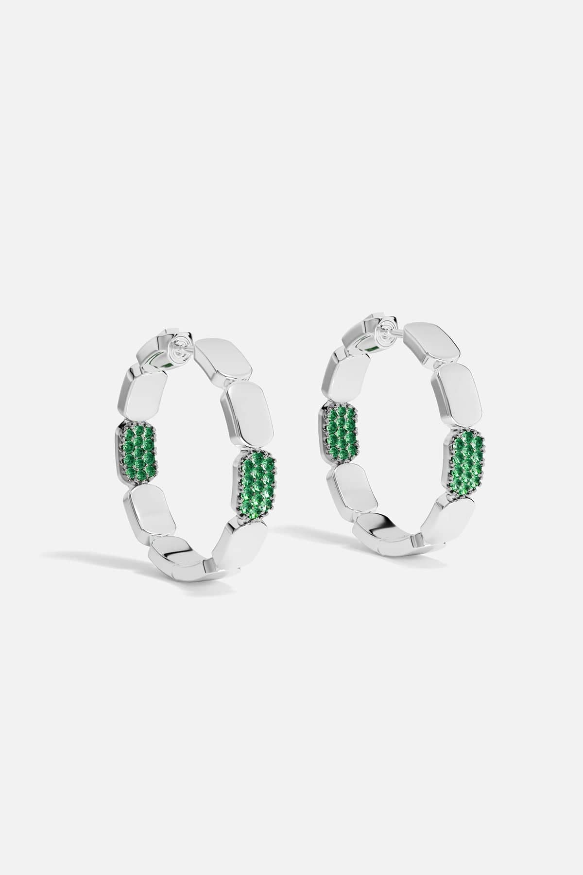 Silver hoop earrings with green stones on a white background