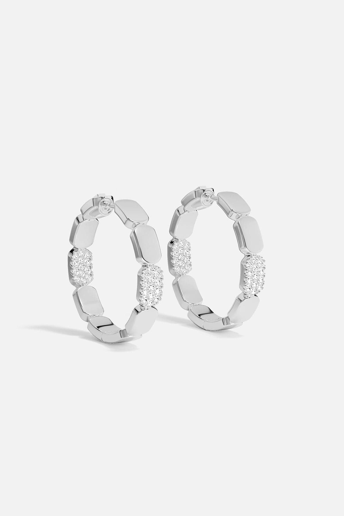 Pair of silver hoop earrings with embedded stones on a white background