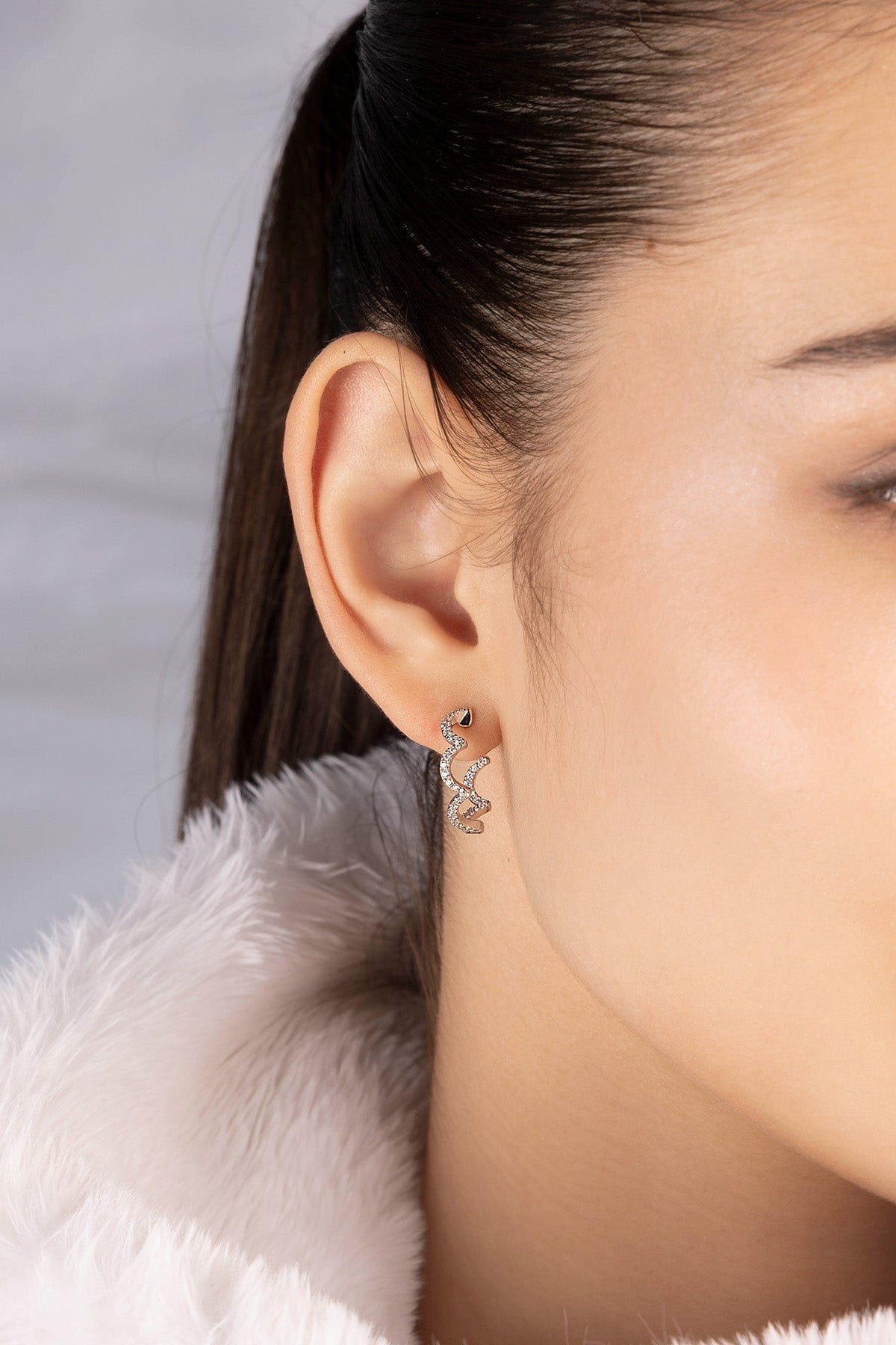 close-up on model wearing silver earrings paved with white stones