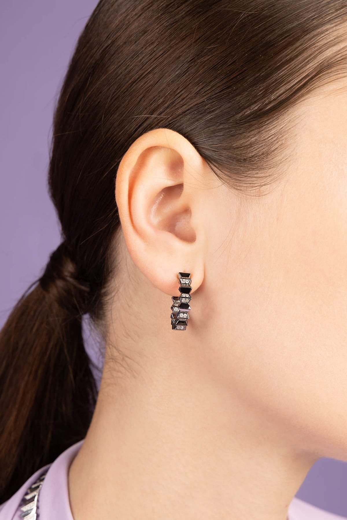 Close-up of an ear wearing a small hoop earring with a blurred background