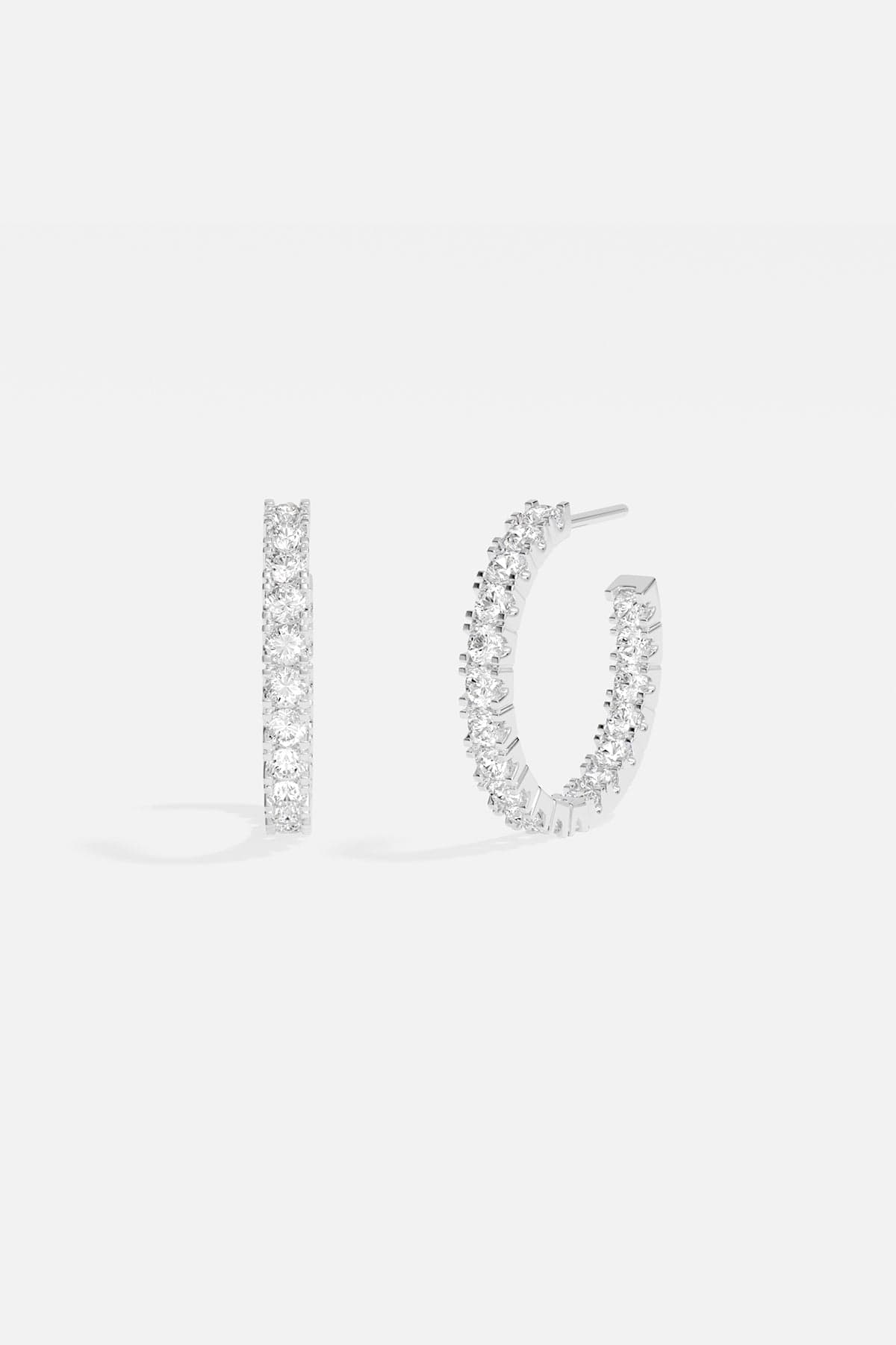Earrings APM Monaco pavé hoop earrings in white silver-tone metal with clear pavé stones.