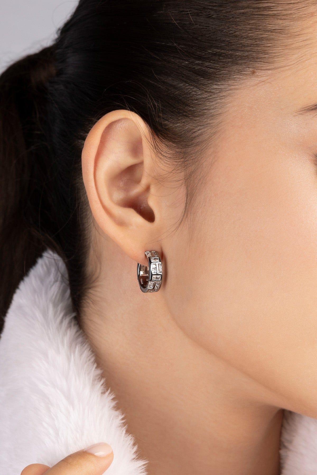 Pair of APM MONACO silver hoop earrings with clear white stones worn on model