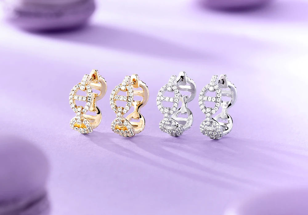 APM Monaco Maille Marine earrings in gold and silver on a purple background