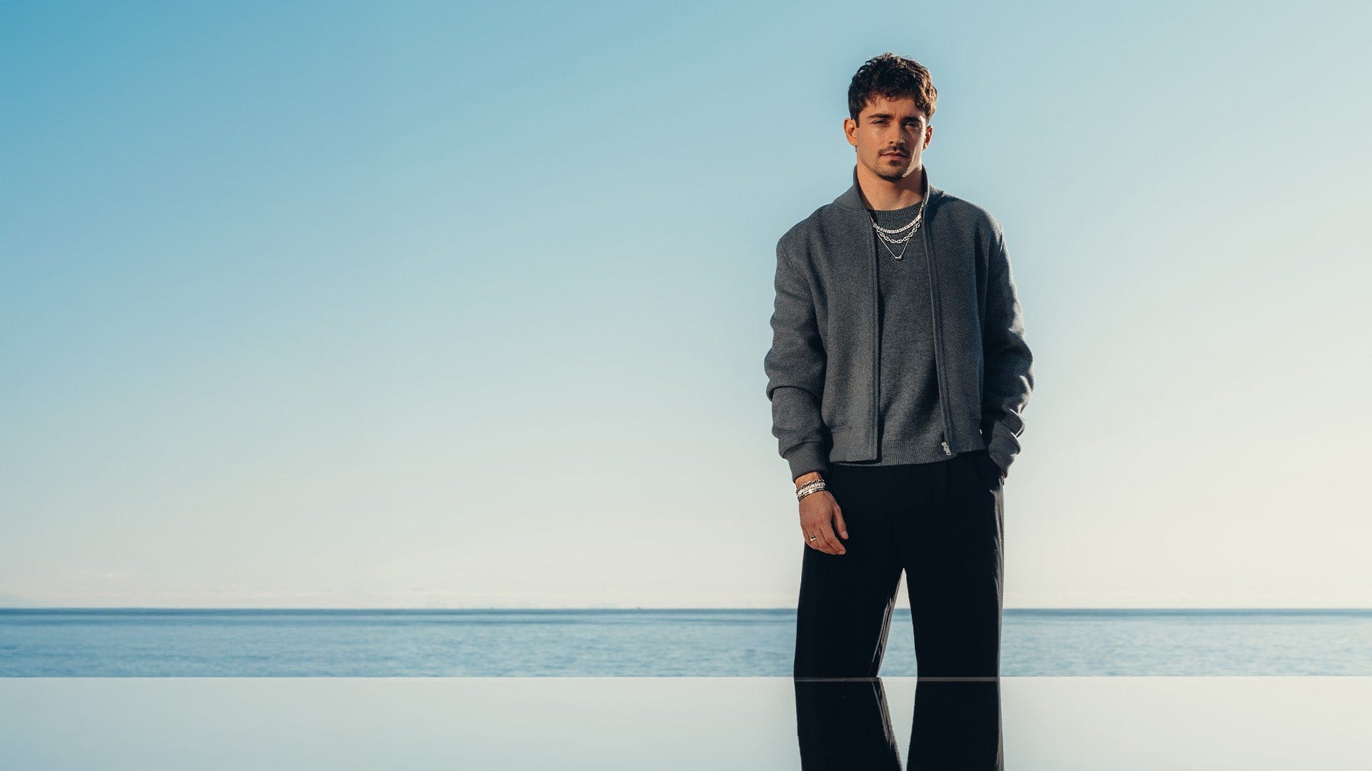 Charles Leclerc standing on a beach with APM MONACO unisex jewelry set in silver