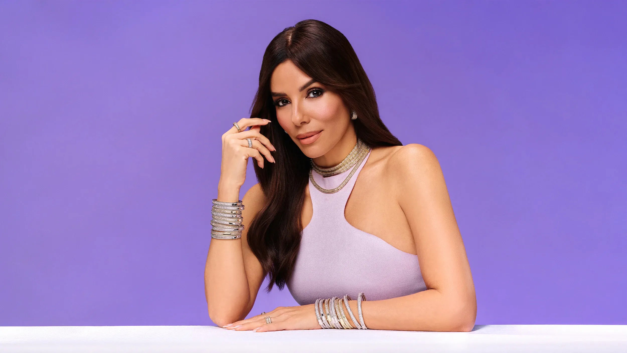 Eva Longoria in a lavender dress with APM Collection Printemps jewelry on a purple background