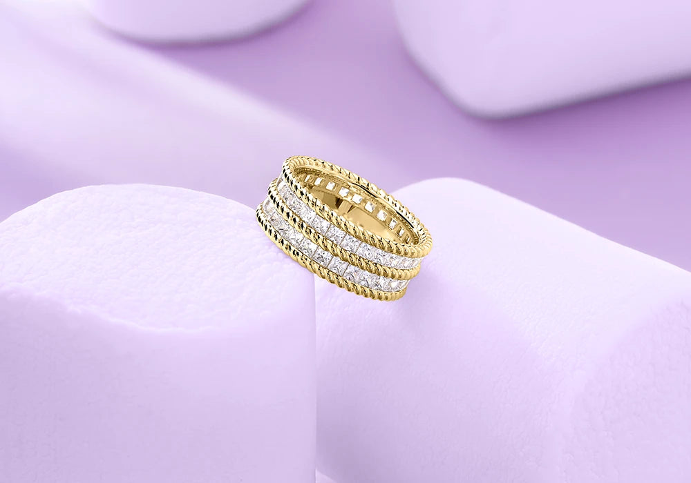 APM MONACO torsade rings in yellow gold and silver on light purple marshmallows