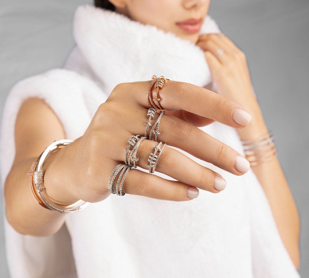 Hand wearing multiple APM MONACO sliding rings with a blurred background