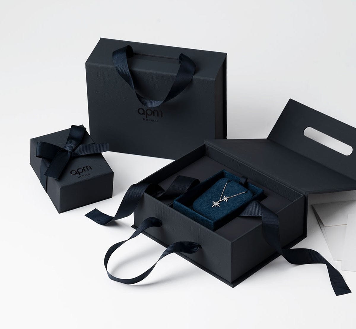 APM jewelry box with a necklace and blue ribbon on a white background