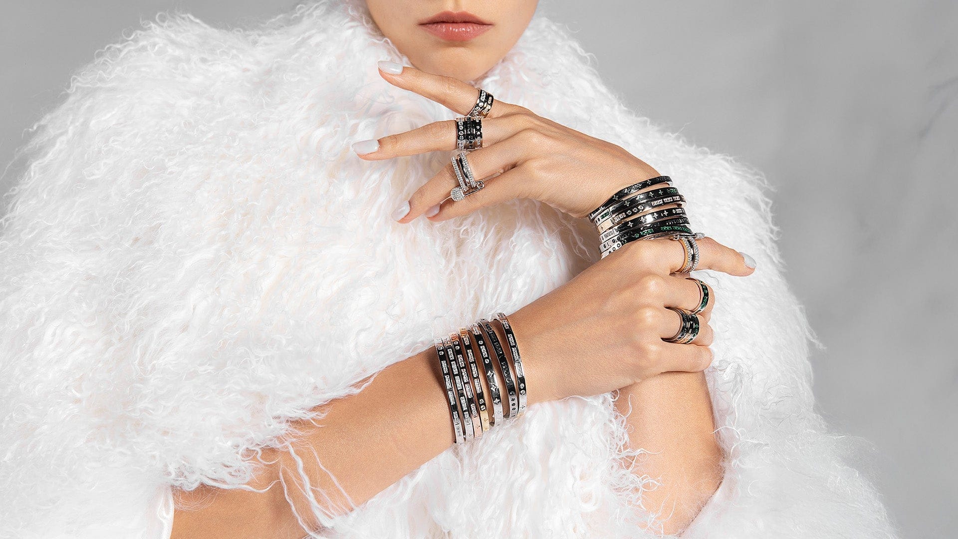 Person wearing multiple APM MONACO morse code rings and bracelets on a white background