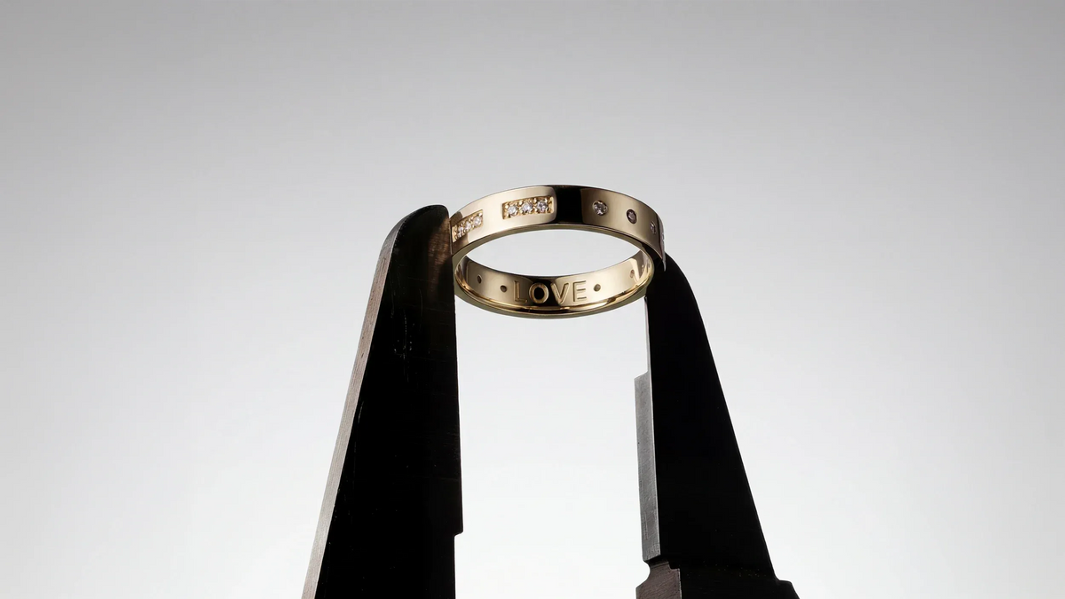 APM Monaco Gold ring with 'LOVE' engraving on a gray background