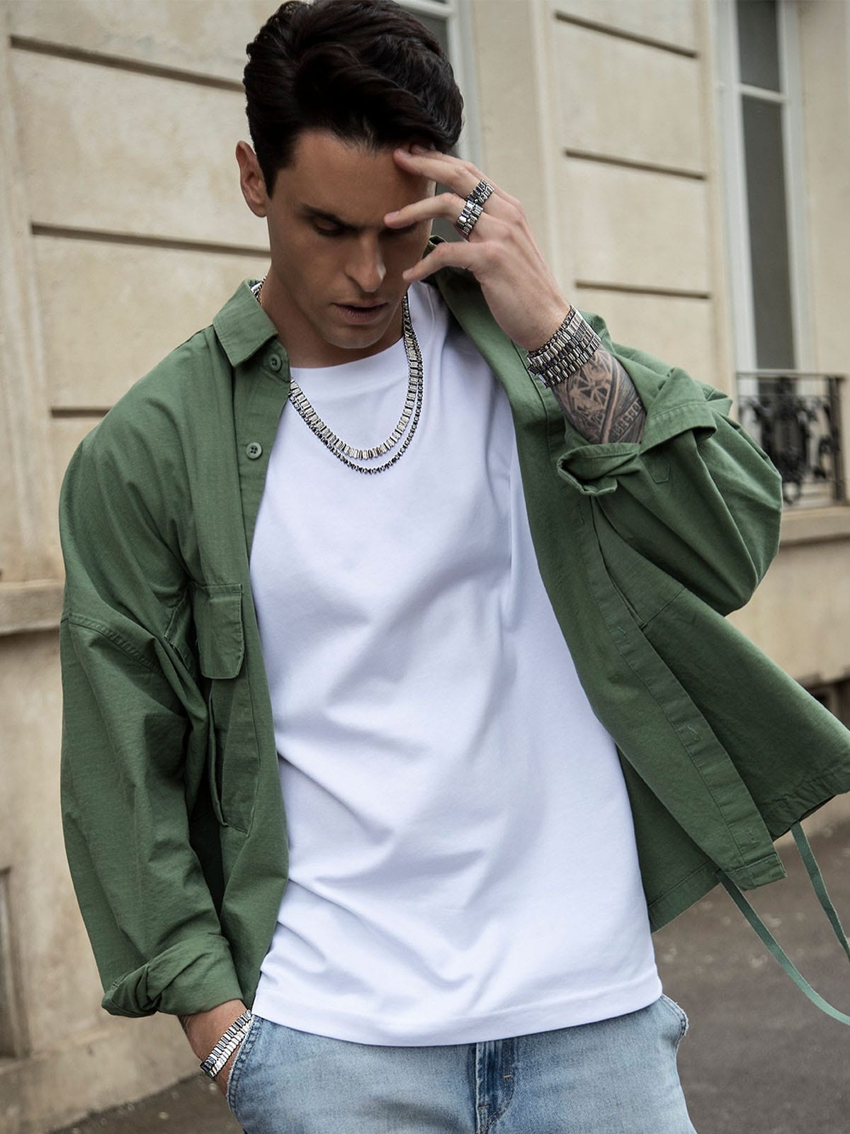 Man wearing a green jacket over a white t-shirt with APM MONACO up and down jewelry set