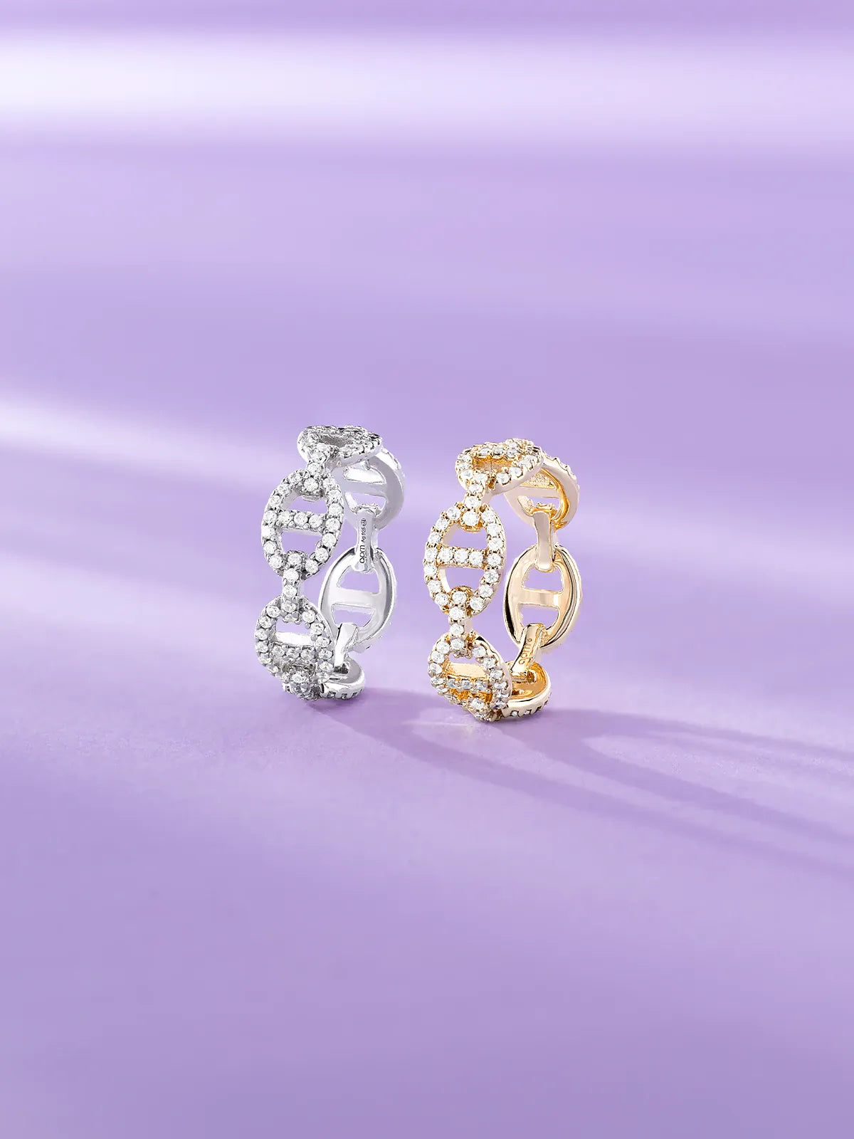 Two APM Yacht Club rings, one silver and one gold, on a purple background