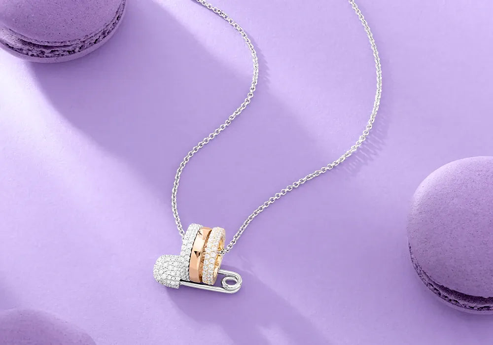 APM Monaco Safety Pin Necklace on a purple surface with macarons