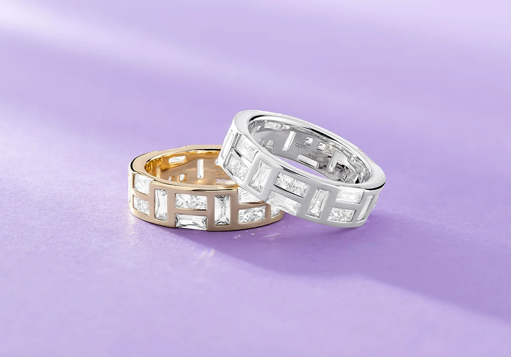 Two APM Monaco ice rings, one gold and one silver, on a purple background