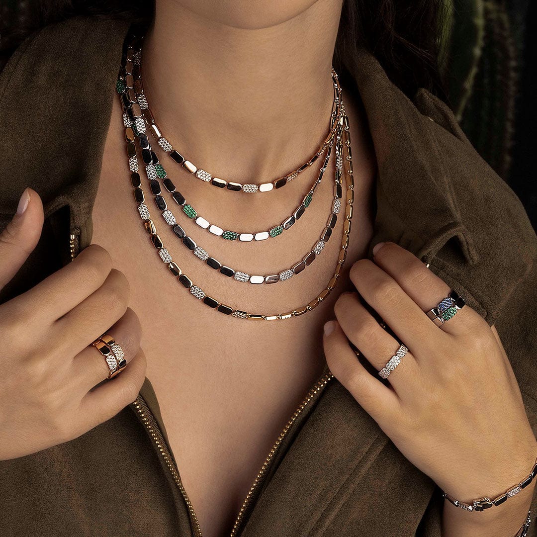 Person wearing multiple necklaces and rings with a blurred background