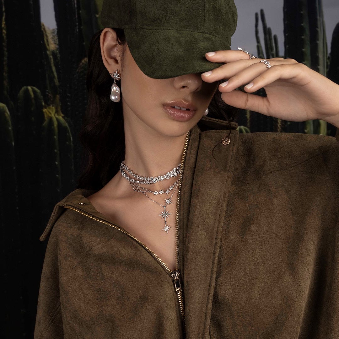 Woman wearing a green cap, brown jacket, and APM MONACO jewelry with a cactus background