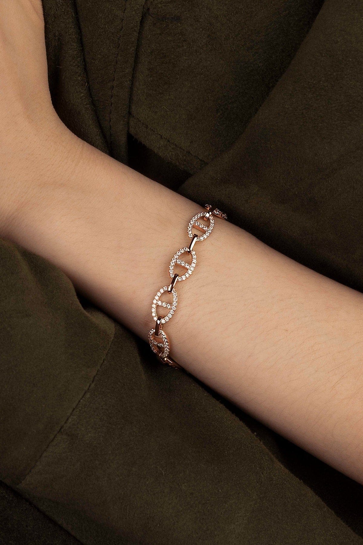 Rose gold bracelet on a wrist against a dark background