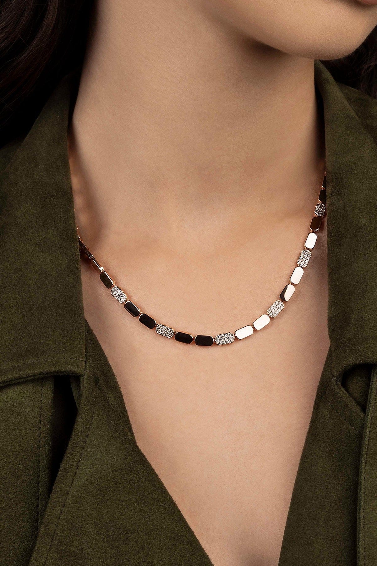 Necklace with rose gold beads worn by a model in an olive green outfit.