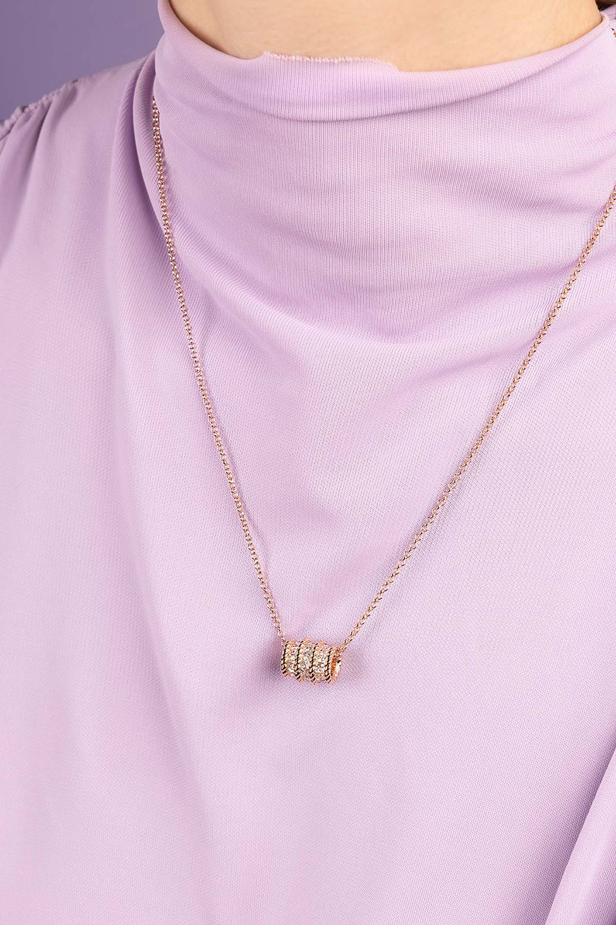 Necklace with a cylindrical pendant on a person wearing a light purple outfit