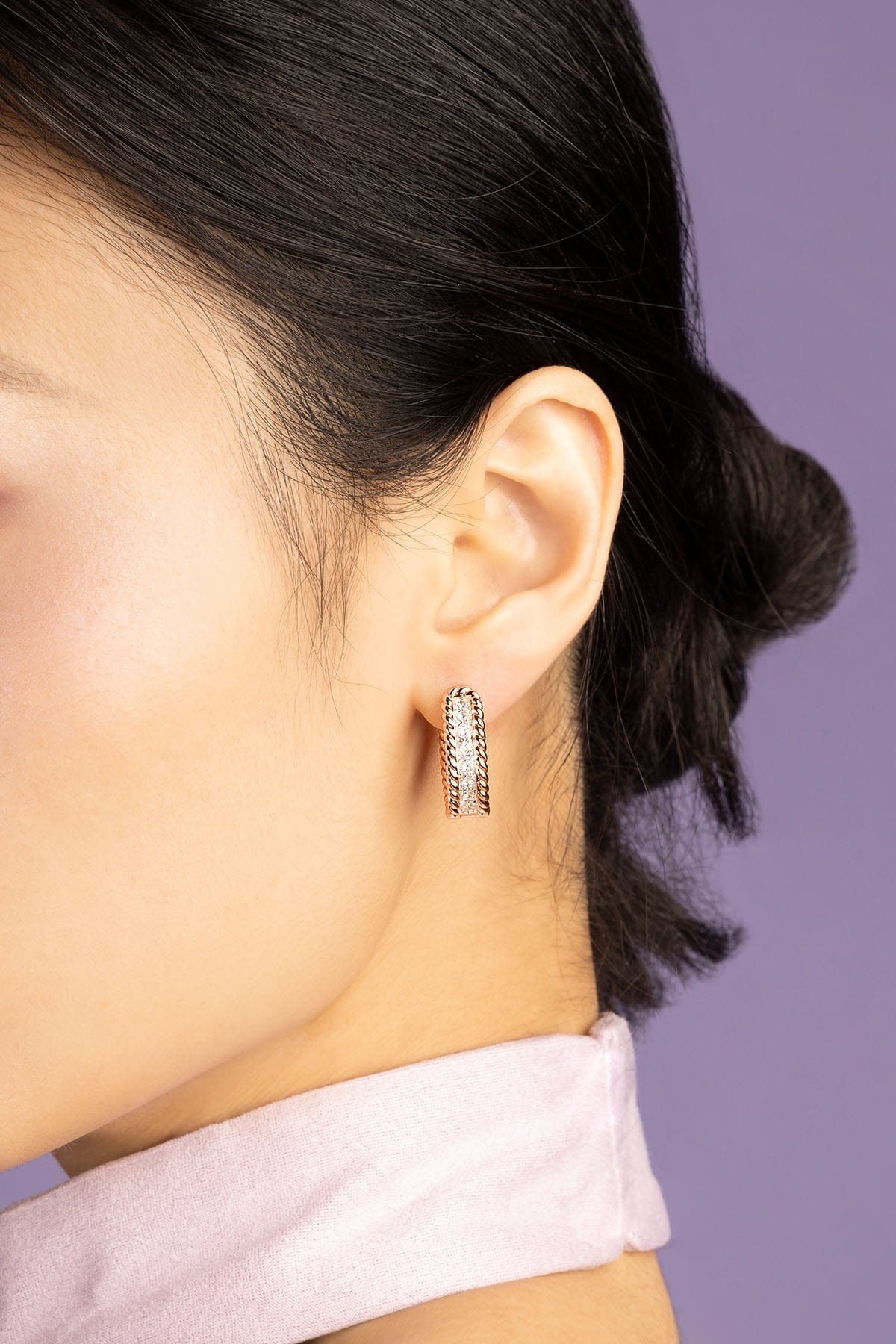 Model wearing rose gold hoop earrings paved with square zirconia stones