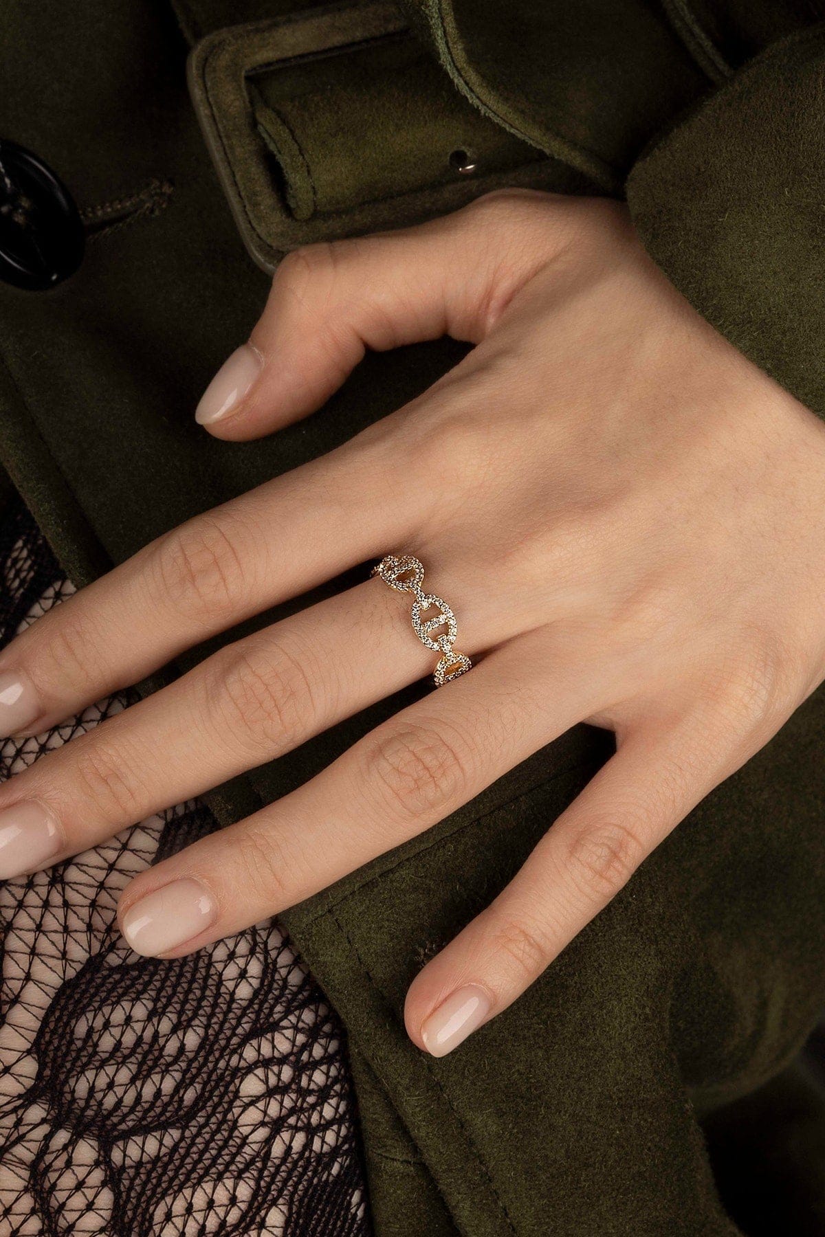 Hand wearing a diamond ring with a dark coat background