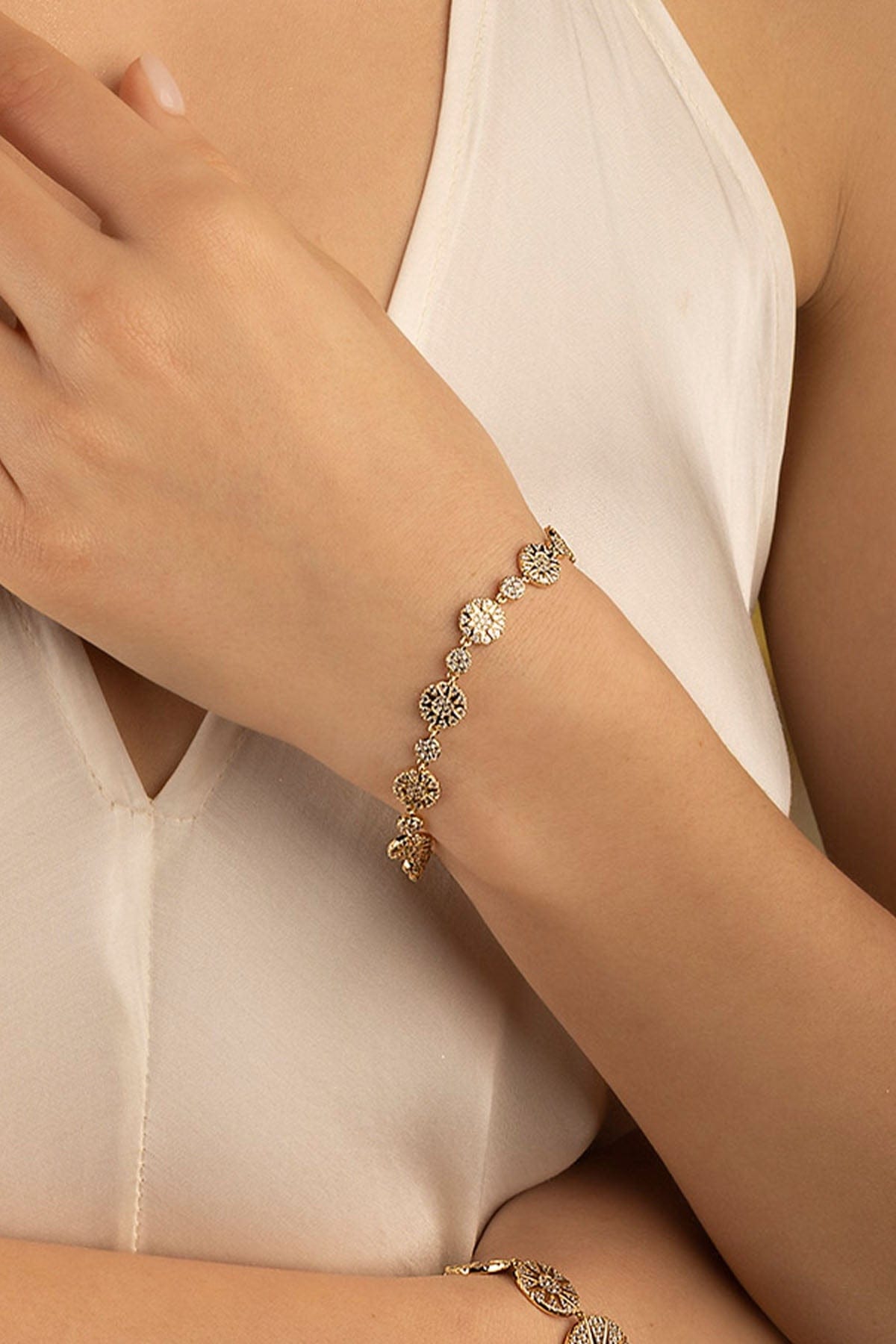 Bracelets APM Monaco: yellow gold floral link bracelet on a woman's left wrist.