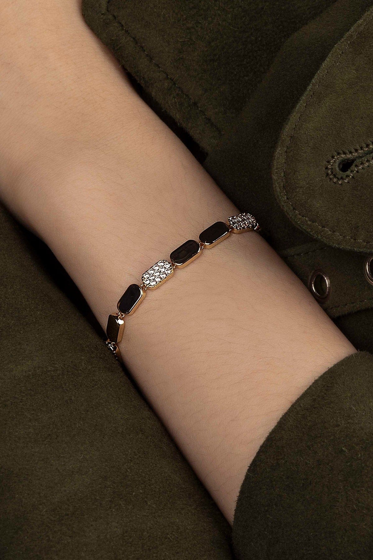 Bracelet with black and gold stones on a wrist against a dark background