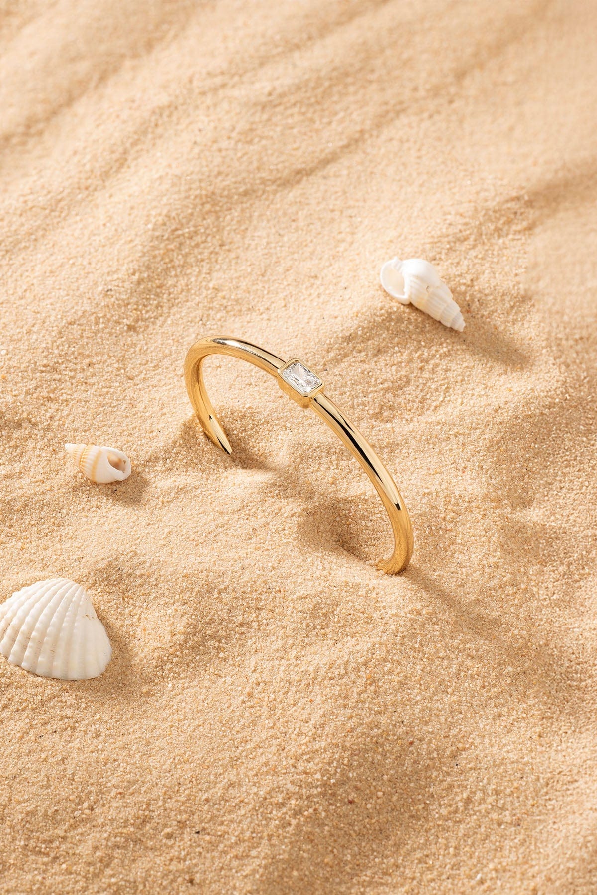 APM Monaco Éclat Cuff in Yellow Gold on sand