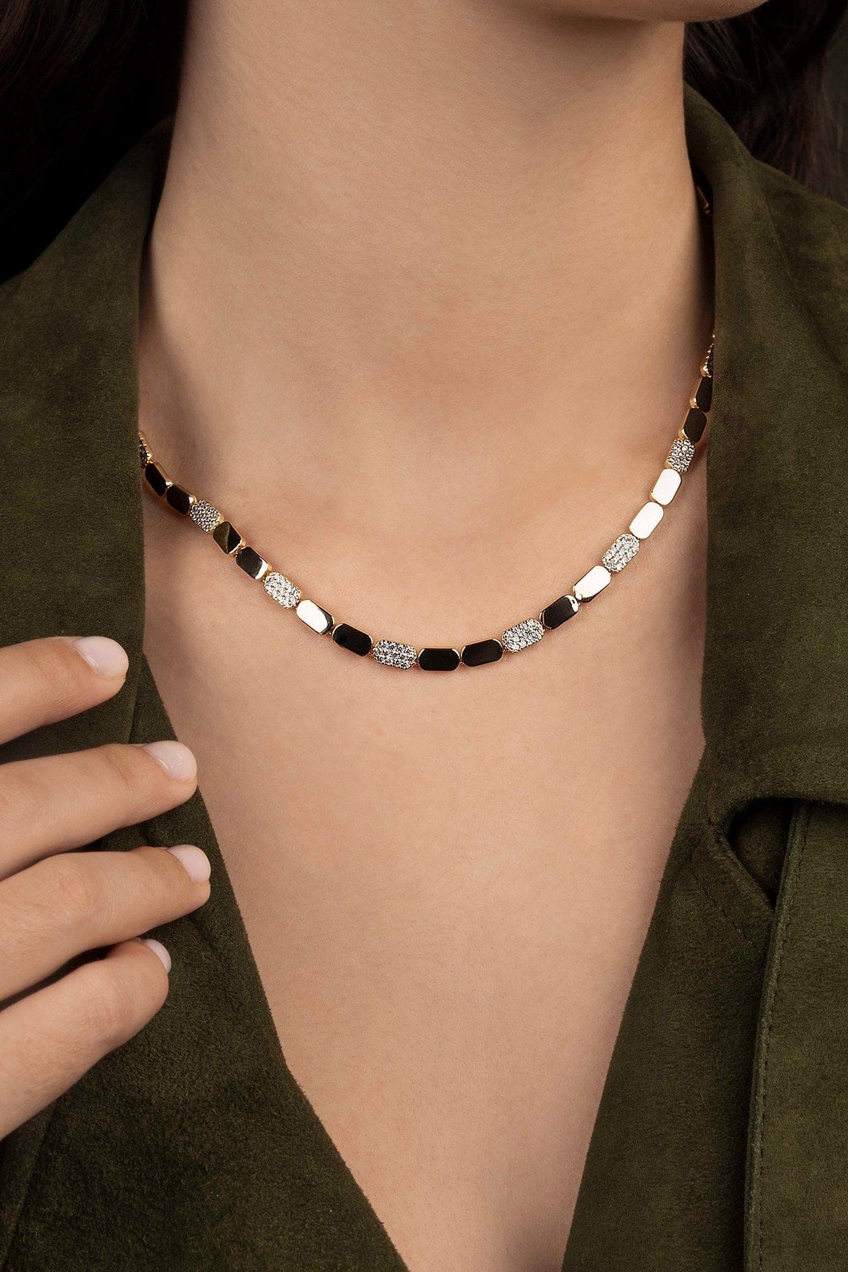 Necklace with black and silver beads worn by a person in an olive green outfit.