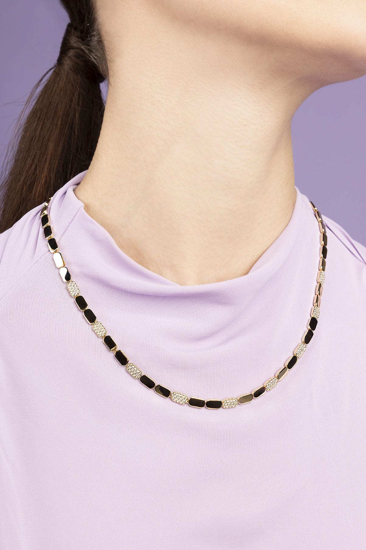 APM MONACO DAINTY gold adjustable necklace worn by a person against a purple background
