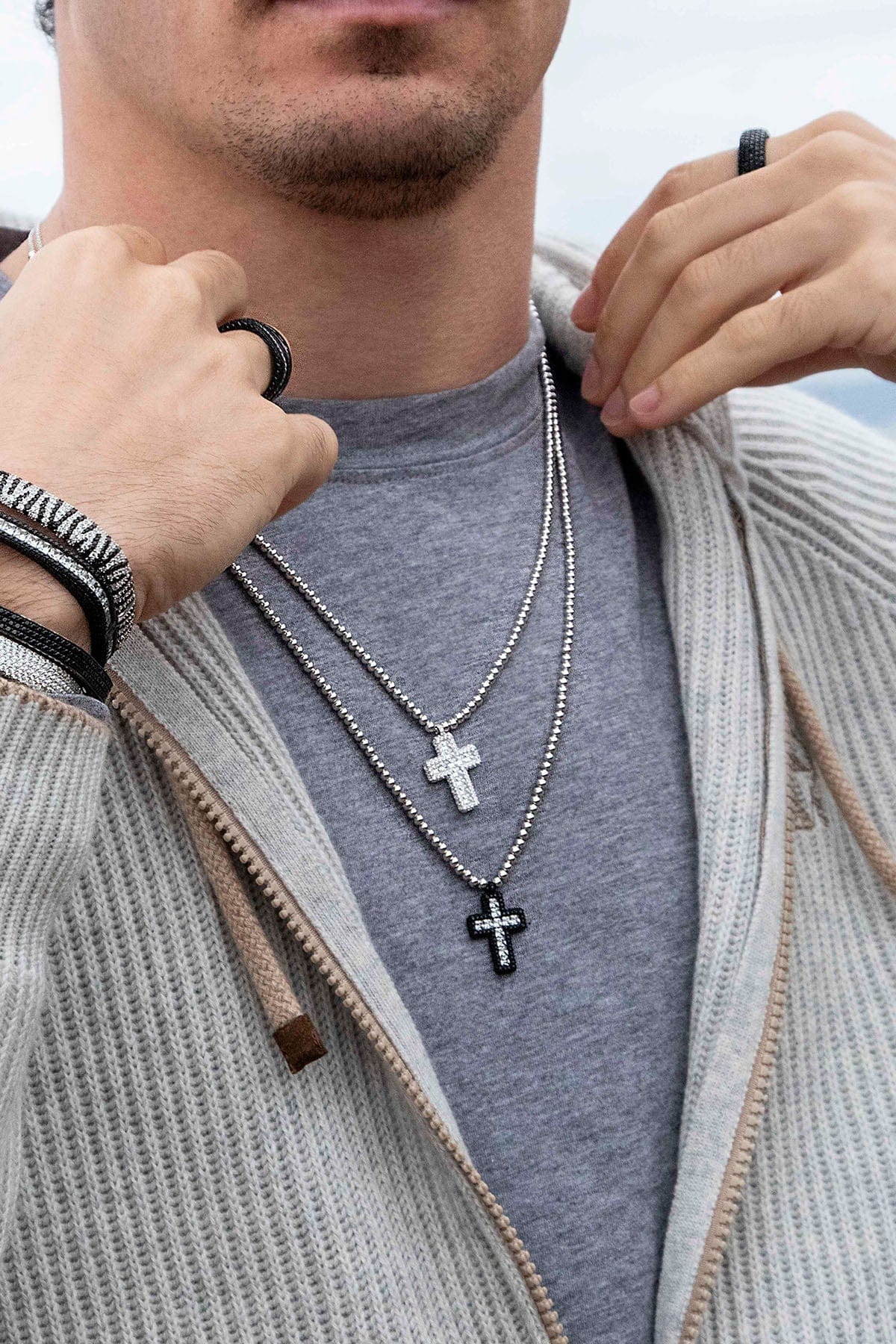 Necklaces APM Monaco; silver-tone chain with two cross pendants—one white cross and one black cross adorned with white stones.